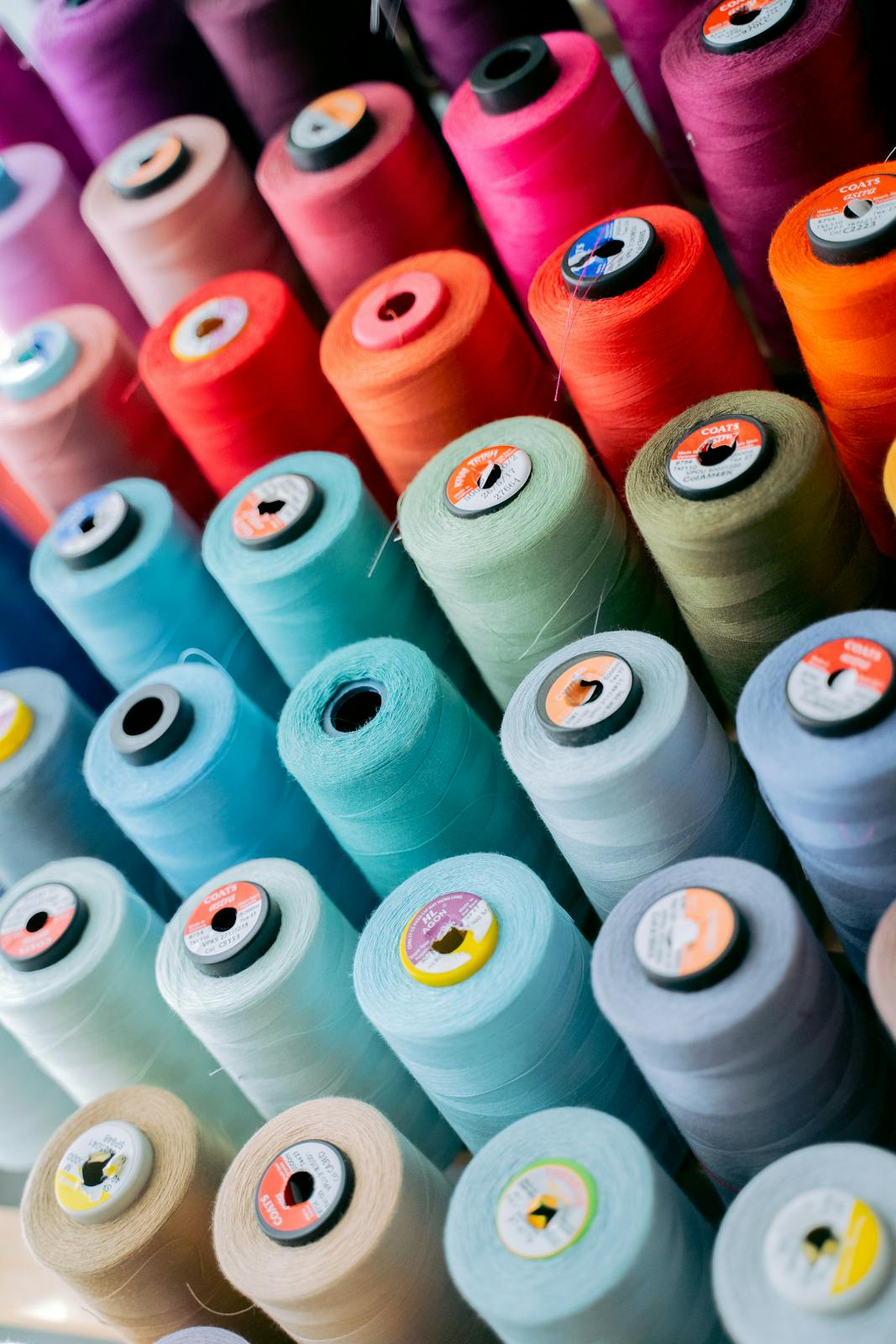 Vibrant spools of sewing thread arranged in rows, showcasing a spectrum of colors.